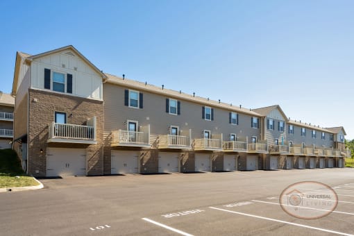 A tan, one story apartment building with balconies and garages.