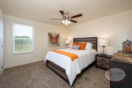 A bedroom with a bed, nightstand, and a ceiling fan.
