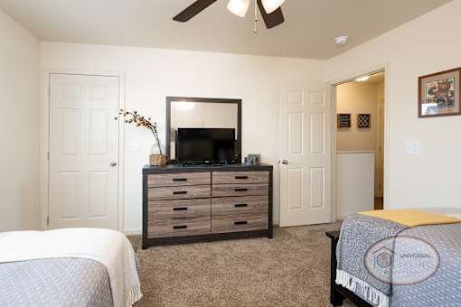 A bedroom with a bed, dresser, and mirror.