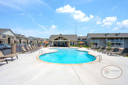 A resort style, saltwater, zero-entry pool with lounge chairs, tables with umbrellas, and a grilling station.
