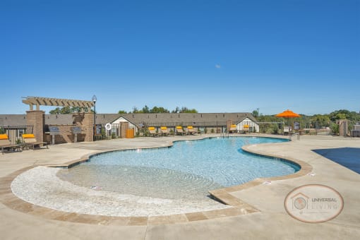 A resort style, saltwater, zero-entry pool with lounge chairs, tables with umbrellas, and a grilling station.