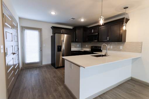 A modern kitchen with dark cabinets and a white island with quartz countertops