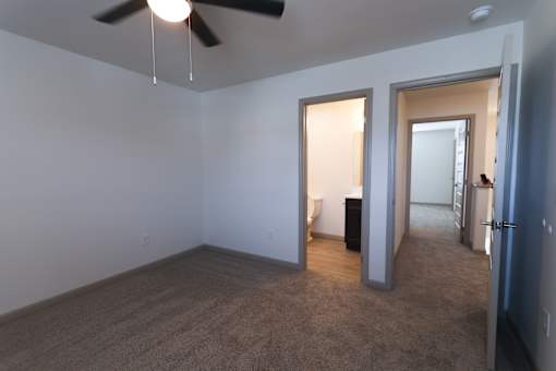 Upstairs  bedroom with a ceiling fan and carpeted floor.
