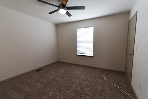 A room with a ceiling fan and a window with blinds.