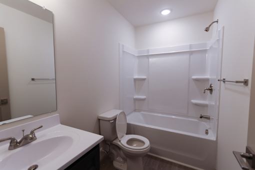 A white bathroom with a toilet, sink, and bathtub.