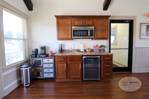 A coffee bar with mini fridge and microwave.