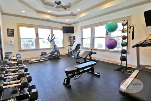 A fitness center with a wall of mirror and an orange accent wall, featuring weight training equipment and cardio equipment.