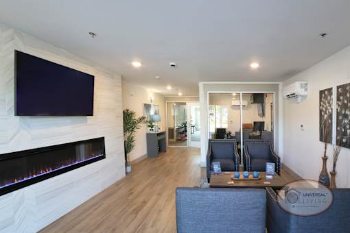 The leasing office with flat screen TV, fireplace, lounge seating, and desk with computer.