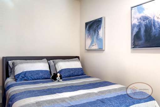 A bed with blue and white striped bedding and art hanging on the wall.