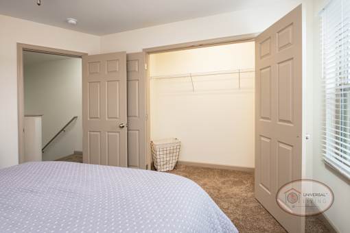 A bedroom with a large closet and carpet.