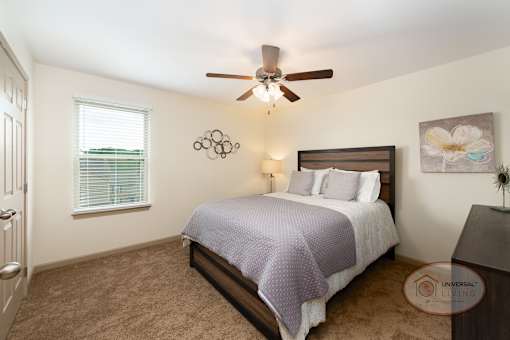 A bedroom with a bed, a ceiling fan, and carpet.