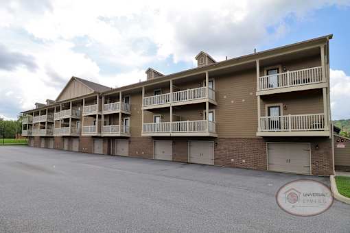 The rear of one bedroom stacked apartment homes with balconies and garages.