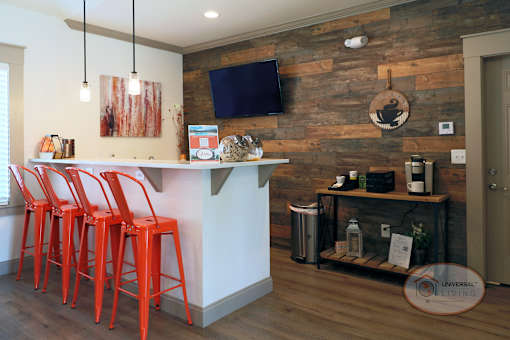 The clubhouse coffee bar with wood accent wall, flat screen TV, and orange bar stools.