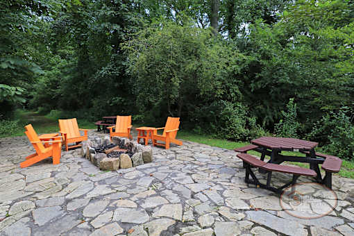 A fire pit surrounded by orange chairs and a picnic table.