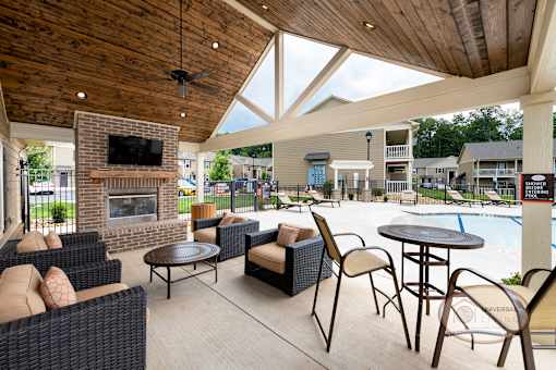 The poolside lounge with flat screen TV, fire place, and a table with chairs.
