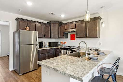 A kitchen with quartz counter tops, dark cabinets, and stainless steel appliances.