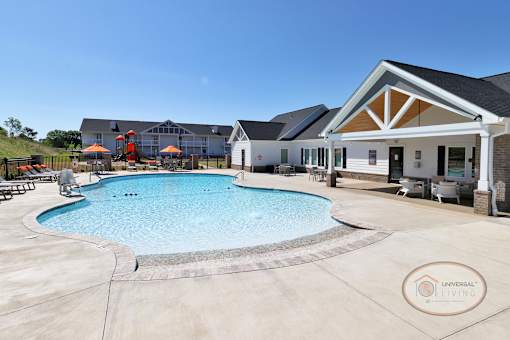 A swimming pool surrounded by lounge chairs with apartment buildings in the background.