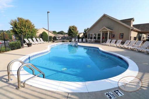A swimming pool with lounge chairs in front of the property clubhouse.