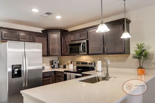 A kitchen with white counter tops, dark cabinets, and stainless steel appliances.