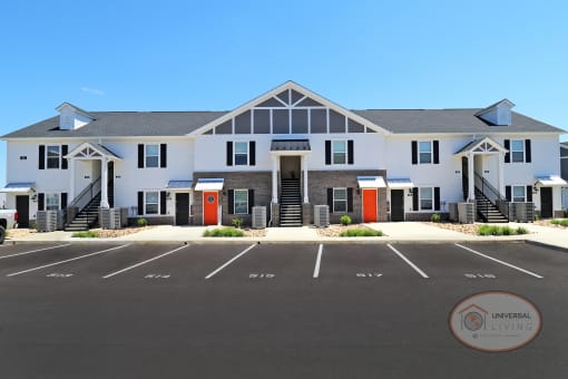 A one bedroom, stacked apartment home with grey and white siding, orange doors, and double staircases.