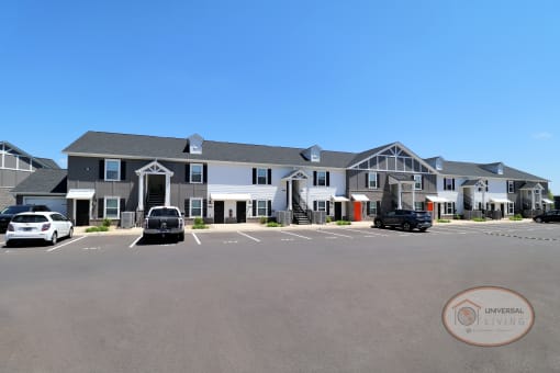 A one bedroom, stacked apartment home with grey and white siding, orange doors, and double staircases.