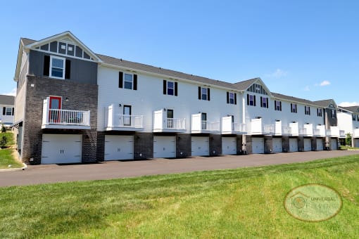 A large, white and gray, 2 and 3 bedroom apartment building with drive under garages and balconies.