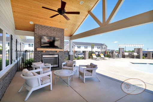 A poolside covered lounge with fireplace, flat screen TV, and lounge chairs.