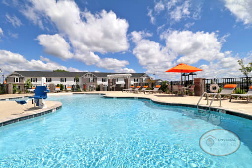 A resort style, zero-entry, saltwater swimming pool surrounded by lounge chairs with apartment homes visible in the background.