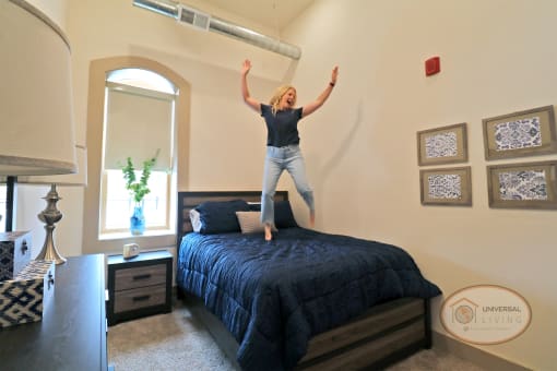 A woman jumping on a bed in a bedroom.
