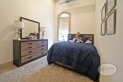 A woman laying on her bed reading a book in a bedroom.