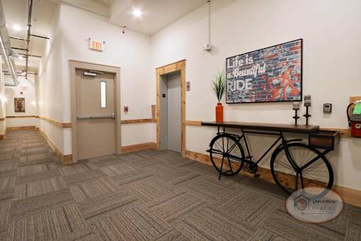 A hallway with a door leading to the staircase and an elevator with a bike-shaped table nearby.