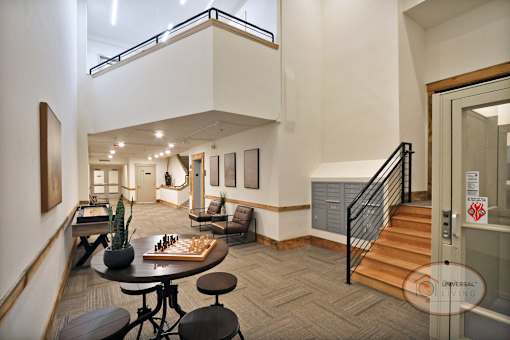 A living room with a staircase and a chess board on the table.