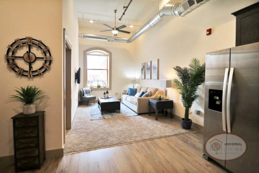 A living room with white walls, white carpet, furnished with a couch and stainless steel appliances.