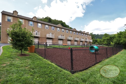 a fenced in yard with a playground in front of an apartment building