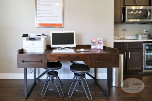 a desk with a computer and three stools in a kitchen
