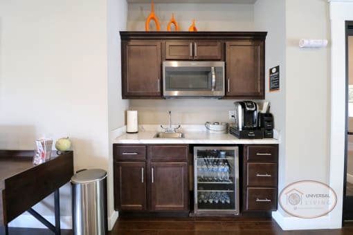 a kitchen in a hotel room with a sink and a microwave