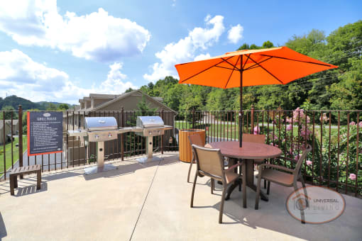a patio with a table and chairs and an orange umbrella