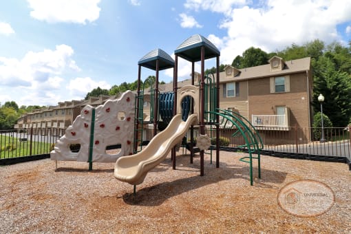 a playground with a slide and climbing equipment in front of a building