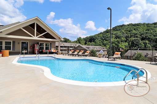 A resort style saltwater swimming pool with zero entry, lounge chairs, grills, and the clubhouse in the bakground.