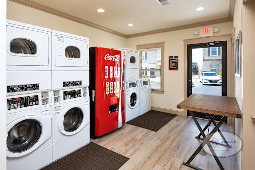 An on-site laundry center with washers, dryers, a vending machines, and table.