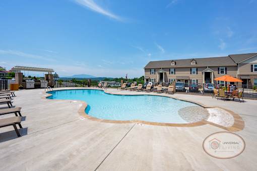 A zero entry pool with lounge chairs and apartments in the background.