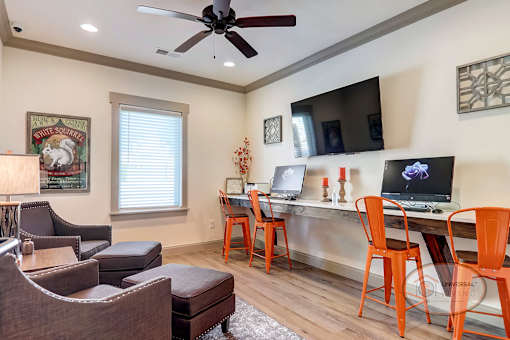 The business center with computers, printers, and free Wi-Fi, as well as lounge seating and a ceiling fan.