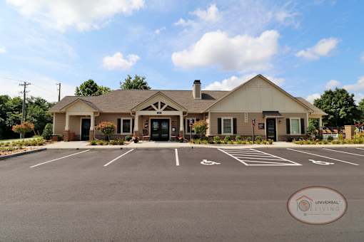 The front of the tan and white clubhouse with ample parking.
