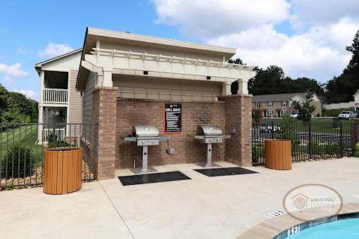 A poolside area with a grills and trash receptacles.