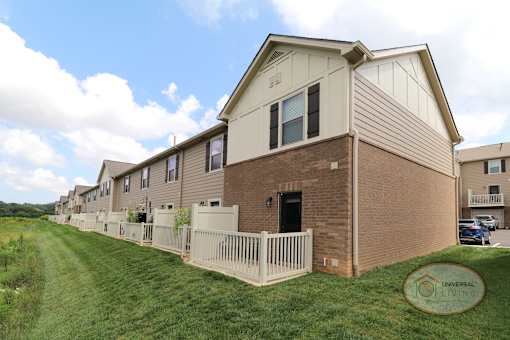 A row of tan apartment homes with brick accents and cream colored patios.