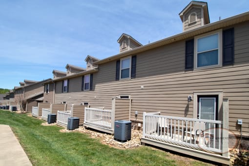 The rear of a row of two and three bedroom apartment homes with patios.