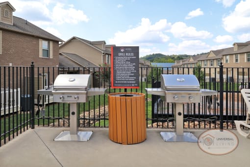Poolside grill station with two stainless steel grills and a trash can.