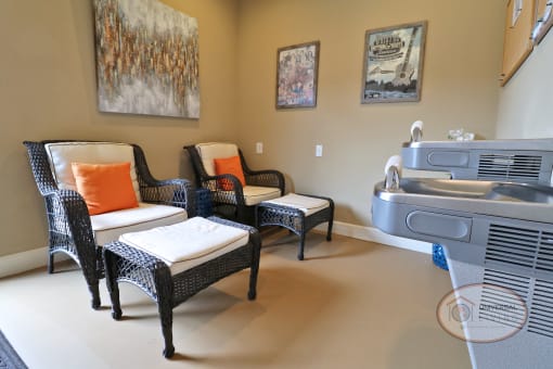 A sitting area with lounge chairs and footstools, water fountains, and a bulliton board.