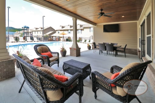 The poolside lounge with flat screen TV, lounge seating, and a table with chairs.
