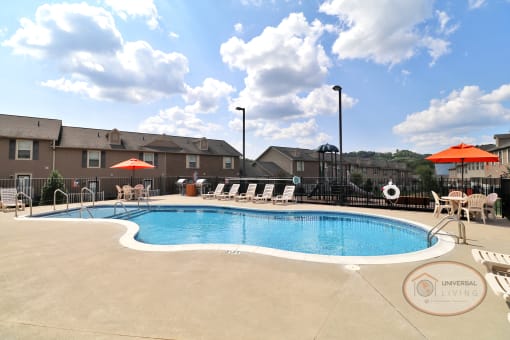 A saltwater pool surrounded by lounge chairs and tables with orange umbrellas.